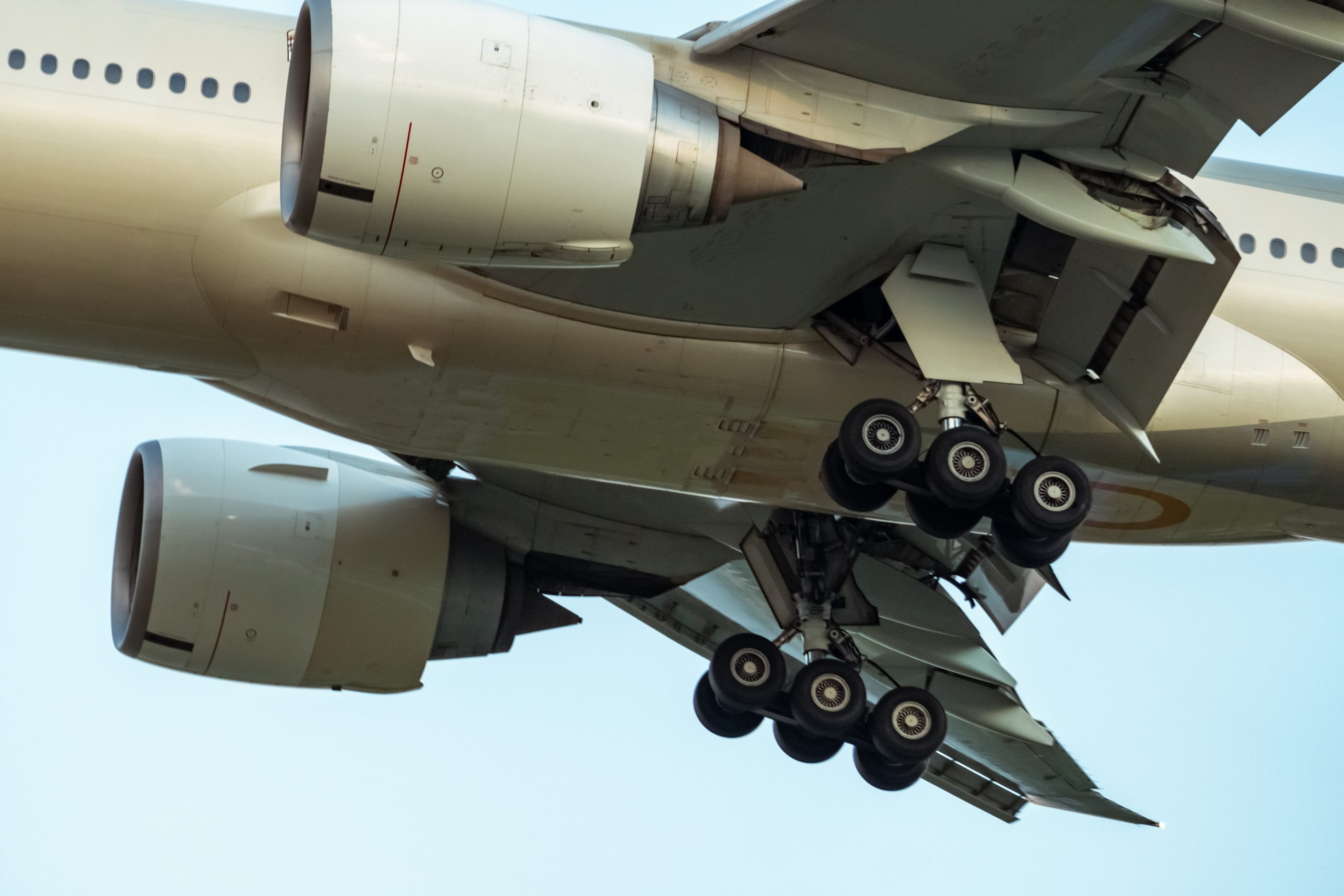 Closeup rubber wheels and chassis of commercial airline. Passeng Closeup rubber wheels and chassis of commercial airline. Passenger plane landing or take off. Aerospace Engineering. Airplane flying on blue sky. Aircraft engine detail at landing or takeoff.
